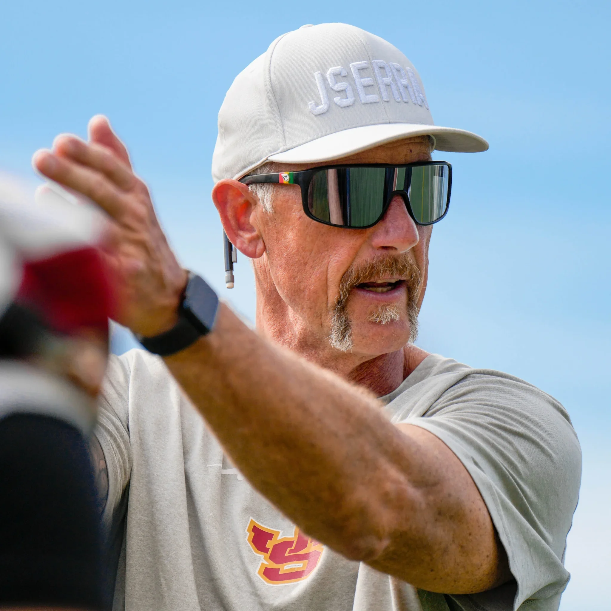 Former NFL offensive tackle and JSerra coach Pat Harlow giving instructions in a JSerra cap and sunglasses.
