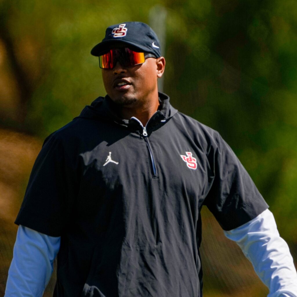 Former NFL linebacker Hardy Nickerson smiling while wearing a red JSerra Catholic High School football shirt and cap.