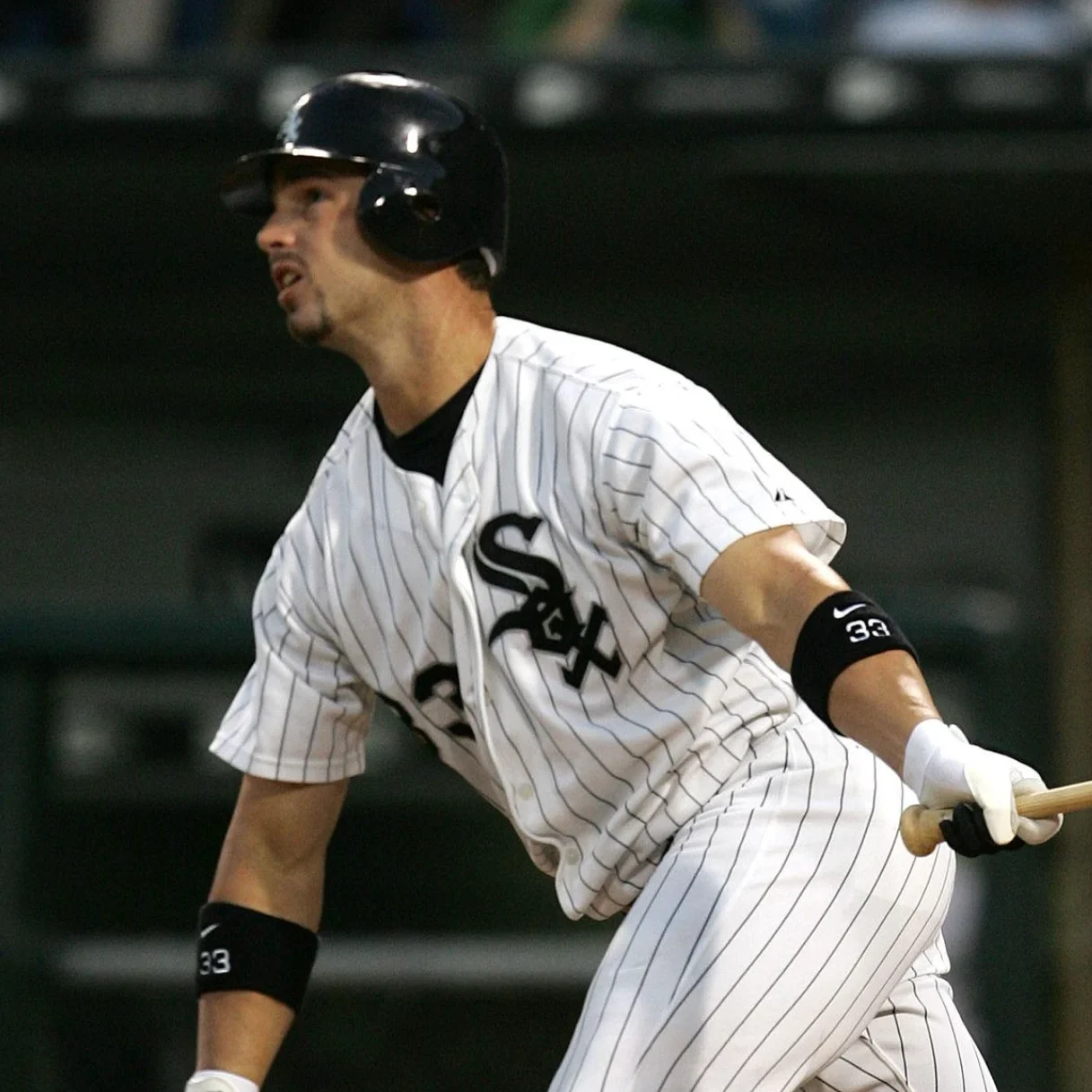Former MLB center fielder Aaron Rowand swinging a wooden bat during a game, wearing his white pinstriped Chicago White Sox uniform and batting helmet.