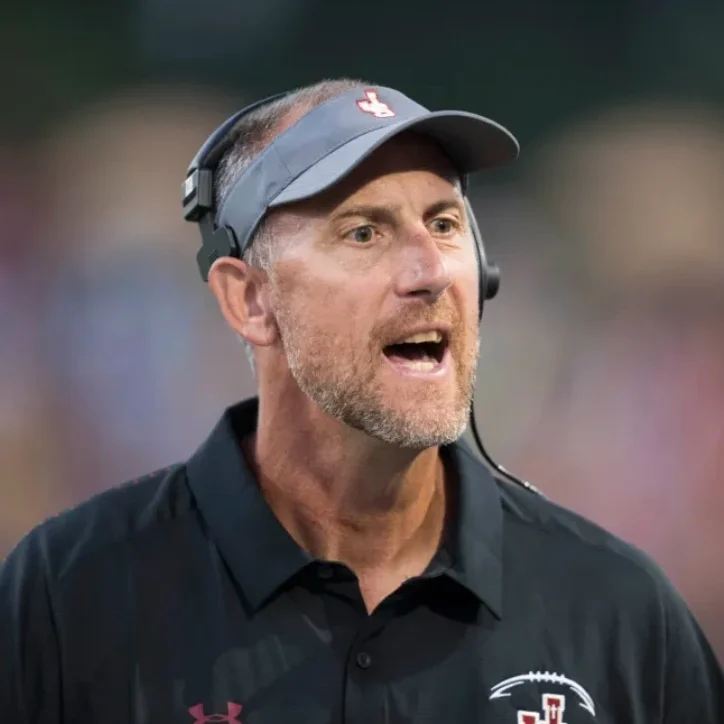 Former NFL player and coach Pat Harlow shouting instructions from the sideline while wearing a JSerra visor.